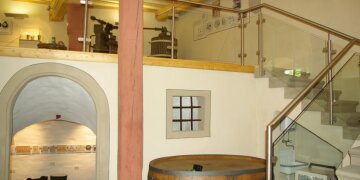 Blick ins Innere des Museums, Treppenhaus und auf einer Etage verschiedene hölzerne Weinpressen