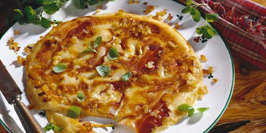 ein Teller mit einem pizzaähnlichen Holzerschmaus dekoriert mit Basilikum
