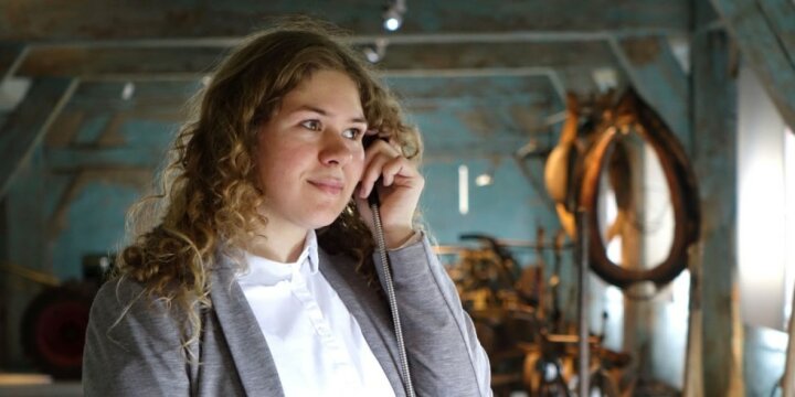 Eine Frau hält den Hörer eines Audio-Guides im Museum an ihr Ohr