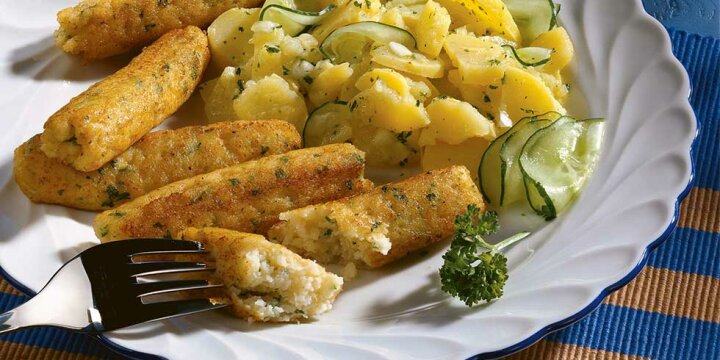 5 Fischwürste zusammen mit Kartoffel-Gurkensalat auf einem Teller